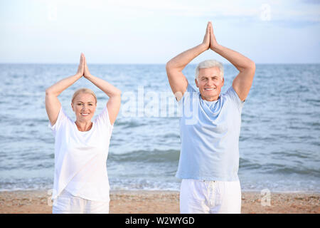 Mature couple practicing yoga at sea resort Stock Photo