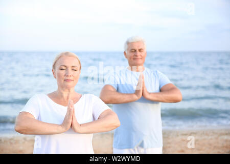 Mature couple practicing yoga at sea resort Stock Photo