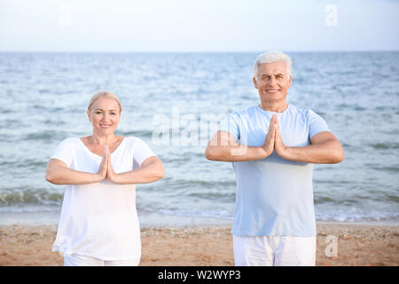 Mature couple practicing yoga at sea resort Stock Photo
