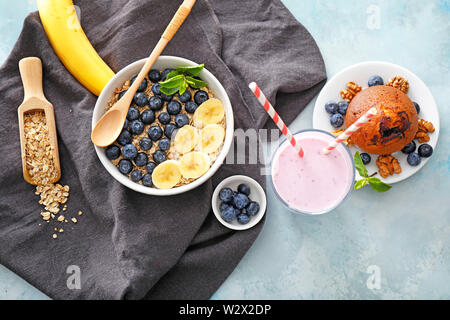 Tasty blueberry yogurt with muffin and oat flakes on color background Stock Photo