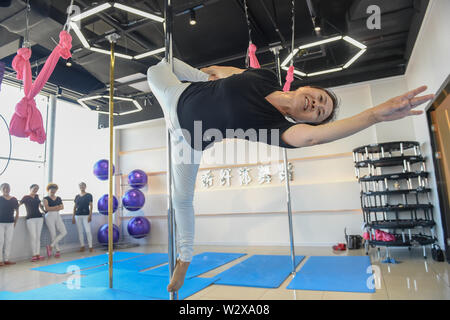 (190711) -- JILIN, July 11, 2019 (Xinhua) -- Jiang Zhijun practices pole dancing in the dance room in Jilin City, northeast China's Jilin Province, July 10, 2019. A group of dama, refering to the legions of usually middle aged women, formed a team of pole dancing in Jinlin City, northeast China's Jilin Province in 2016. The team has eight members with an average age of 64. 'Pole dancing is known for its softness and strength,'says Jiang Zhijun, the 68-year-old team leader.' We started with basic strength training, then went forward to perform high-level moves gradually.' The team competed in m Stock Photo