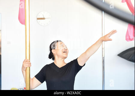 (190711) -- JILIN, July 11, 2019 (Xinhua) -- Jiang Zhijun practices pole dancing in the dance room in Jilin City, northeast China's Jilin Province, July 10, 2019. A group of dama, refering to the legions of usually middle aged women, formed a team of pole dancing in Jinlin City, northeast China's Jilin Province in 2016. The team has eight members with an average age of 64. 'Pole dancing is known for its softness and strength,'says Jiang Zhijun, the 68-year-old team leader.' We started with basic strength training, then went forward to perform high-level moves gradually.' The team competed in m Stock Photo