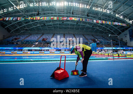 Gwangju, South Korea. 11th July, 2019. A woman sweeps up the lint of the carpet at the edge of the swimmers' competition pool at the Swimming World Championships. Credit: Bernd Thissen/dpa/Alamy Live News Stock Photo