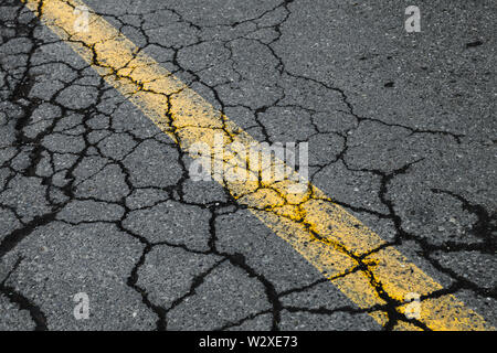 Cracked asphalt road with yellow dividing line. Transportation background texture Stock Photo