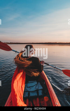 Back view of happy cute girl holding paddle in a kayak on the river Stock Photo