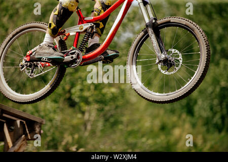 wheels downhill mountain bike jump in drop on background of green forest Stock Photo