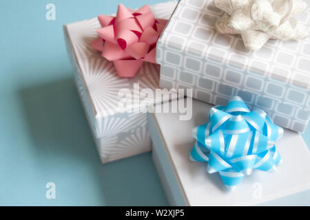 Three light gray gift boxes with light bow on blue background. Festive concept. Stock Photo