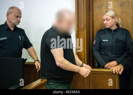 11 July 2019, Lower Saxony, Aurich: The defendant (M) enters the courtroom in handcuffs shortly before the start of the trial. Between 1999 and 2014, he is said to have abused children and adolescents in more than 100 cases in Aurich and Großheide, some of whom were entrusted to him as foster fathers. Photo: Mohssen Assanimoghaddam/dpa - ATTENTION: Defendant was pixelated on court order Stock Photo