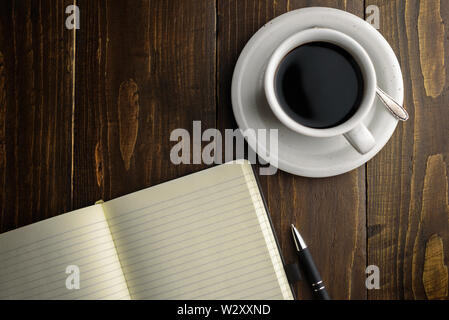 Black coffee, pen and notebook on dark wooden table. Working place Stock Photo