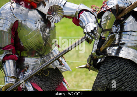 Two medieval knights in armour battle with weapons Stock Photo