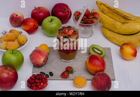 Smoothies from fruits and berries in a glass on a white wooden background. Healthy food, diet. Stock Photo