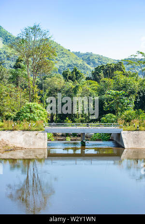 Concrete bridge over the weir in the river ,The background of mountains and trees Stock Photo