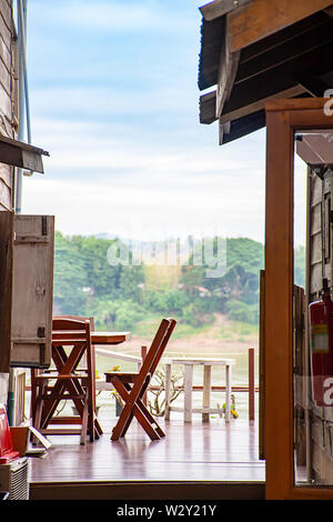 Wooden chairs on the balcony. Background on the Mekong River and the trees at Walking Street Chiang Khan, Loei in Thailand. Stock Photo