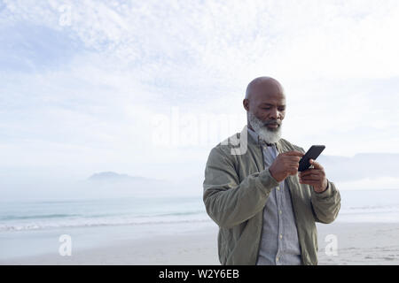 African-American man using a smartphone by the beach Stock Photo