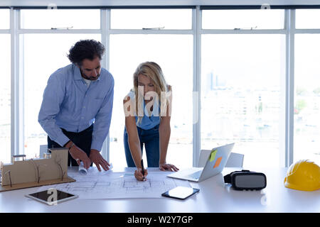 Male and female architect working on blueprint at table in modern office Stock Photo