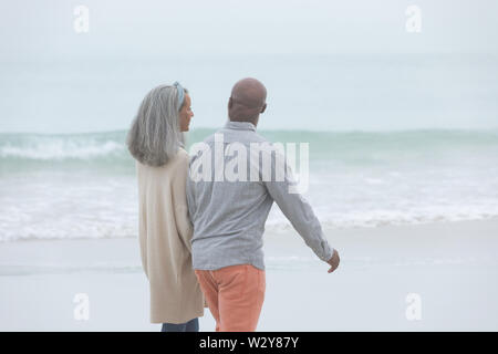Couple holding hands while walking by the beach Stock Photo