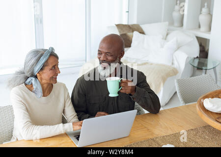 Couple using white laptop on table while man holds a cup Stock Photo