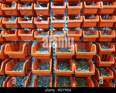 Screws in orange storage boxes in a workshop Stock Photo