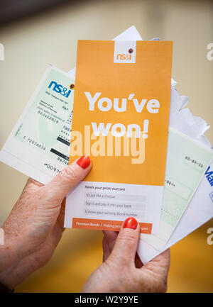 A woman opening a winning Premium Bonds letter with her winners cheque Stock Photo