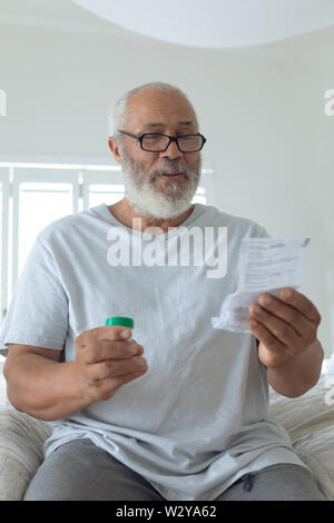 Man wearing glasses while sitting on bed Stock Photo
