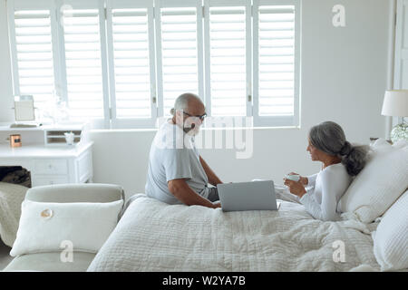 Couple sitting on bed inside a room Stock Photo