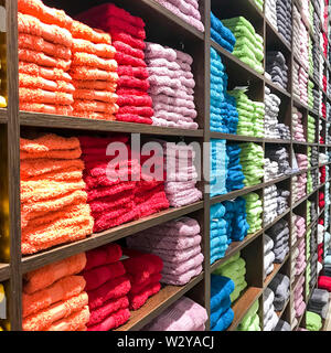 Terry colored towels on shelves in store, sale Stock Photo