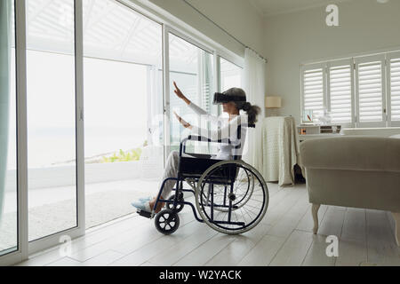 Woman on a wheelchair using virtual reality headset Stock Photo