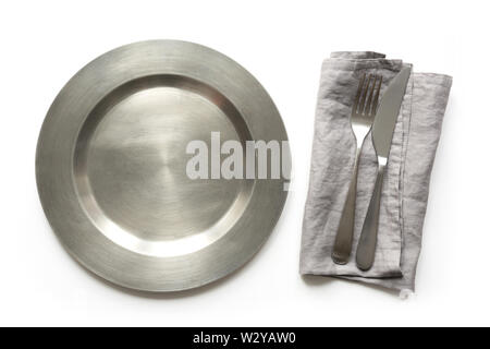 Empty metal dish with knife and fork on white table. Table setting. Stock Photo