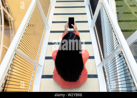 Businesswoman using mobile phone on stairs Stock Photo