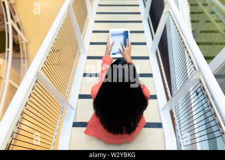 Businesswoman using digital tablet on stairs Stock Photo
