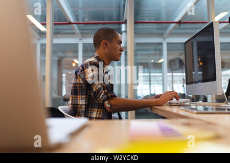 Male graphic designer working on computer at desk Stock Photo