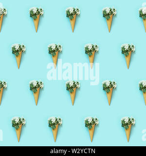 Seamless pattern of white spring flowers in waffle cone on blue background. Spring concept. Top view. Stock Photo