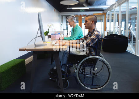 Male and female executive working on computer and laptop at desk Stock Photo