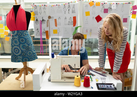 Male fashion designer using sewing machine on a table Stock Photo