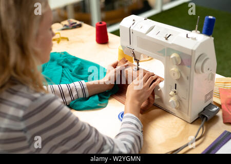 Female fashion designer using sewing machine on a table Stock Photo