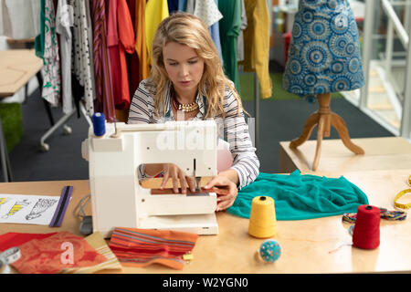 Female fashion designer using sewing machine on a table Stock Photo