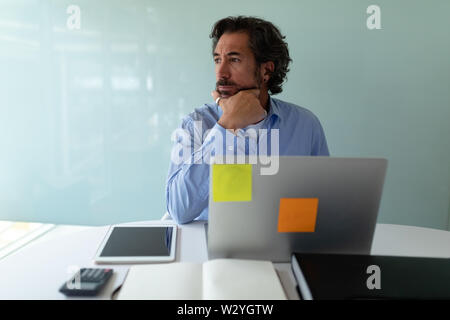 Businessman looking away while working at desk in office Stock Photo