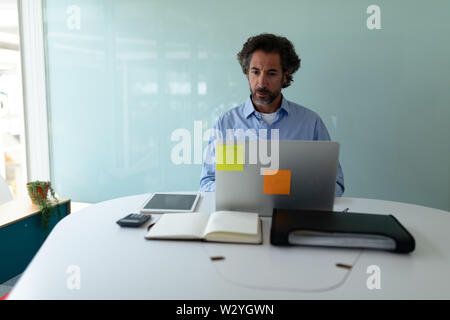 Businessman working on laptop at desk in office Stock Photo