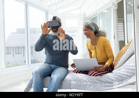 Couple sitting on bed while using digital devices Stock Photo