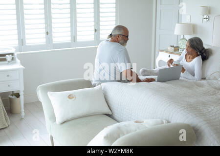 Couple sitting on the bed inside a room Stock Photo