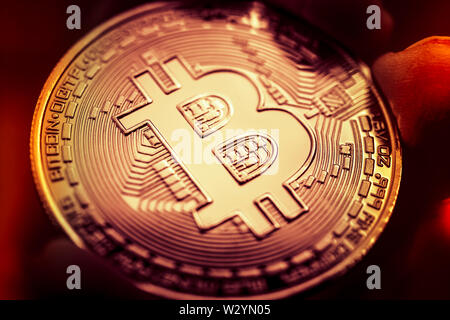 Finger holding Bitcoin coin, virtual currency Stock Photo