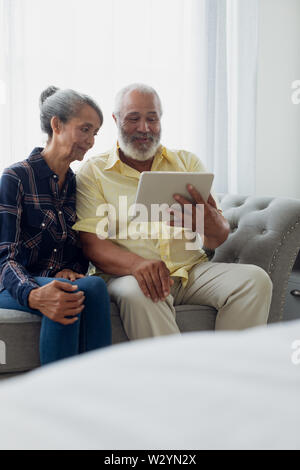 Couple sitting on couch while using a tablet Stock Photo