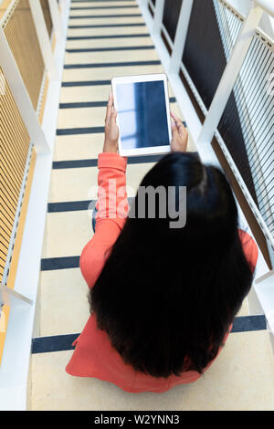 Businesswoman using digital tablet on stairs in office Stock Photo