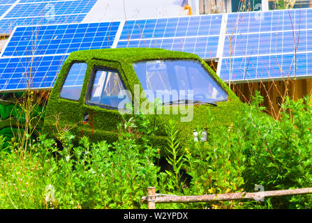 car covered in grass with solar panels in the background Stock Photo