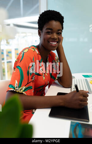 Female graphic designer working on graphic tablet at desk in office Stock Photo