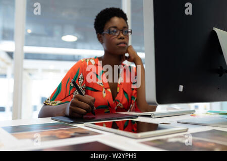 Female graphic designer working on graphic tablet at desk Stock Photo