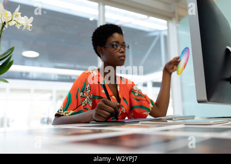 Female graphic designer working on graphic tablet at desk Stock Photo