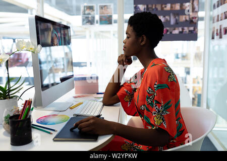 Female Graphic designer using graphic tablet at desk Stock Photo