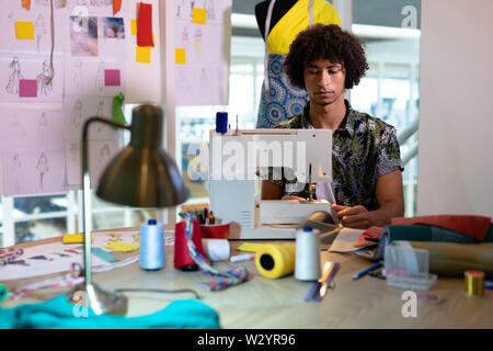 Male fashion designer using sewing machine on a table Stock Photo