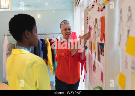 Female fashion designers discussing over sketch design Stock Photo